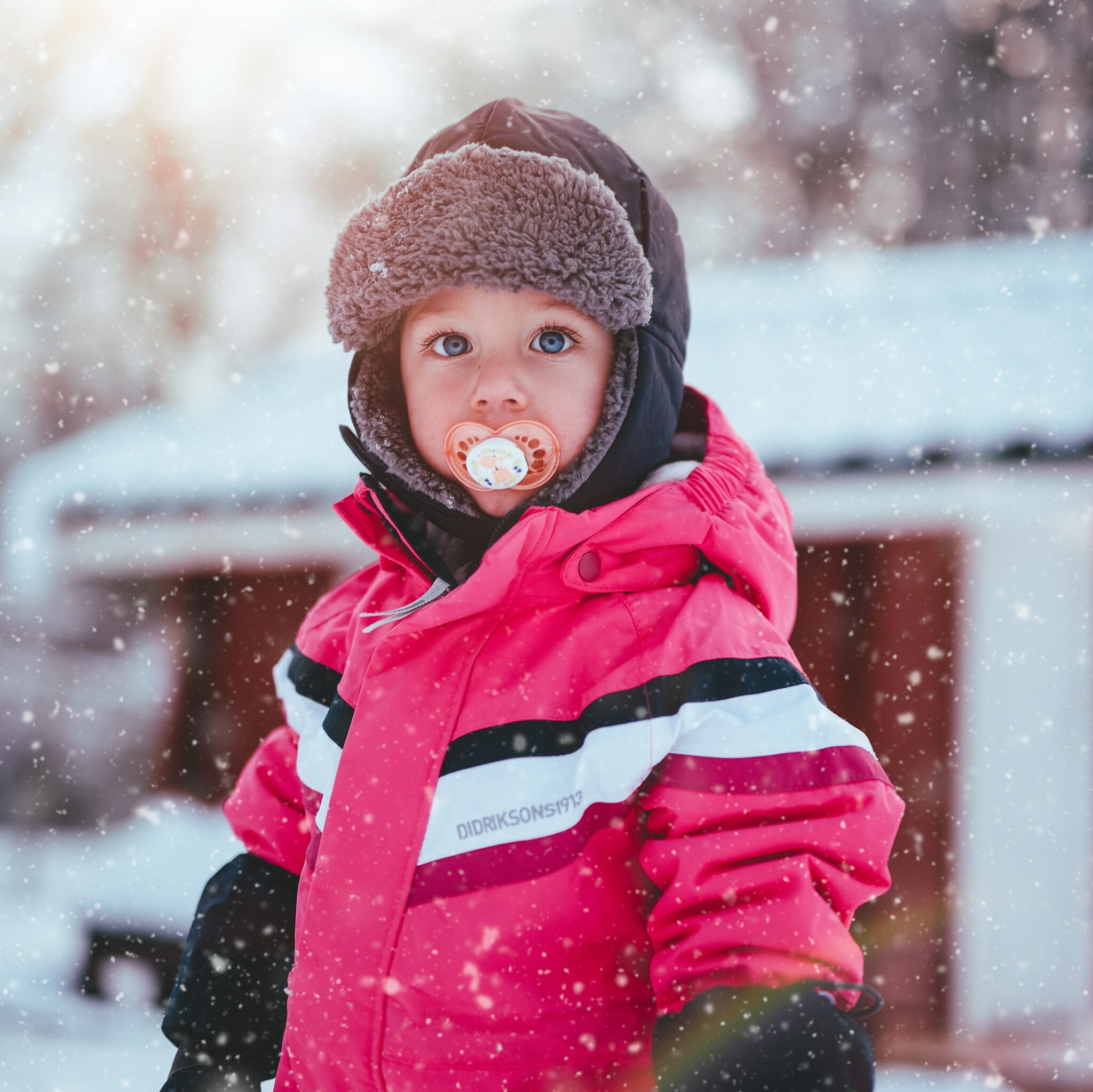 Enfant sous la neige avec sa tétine